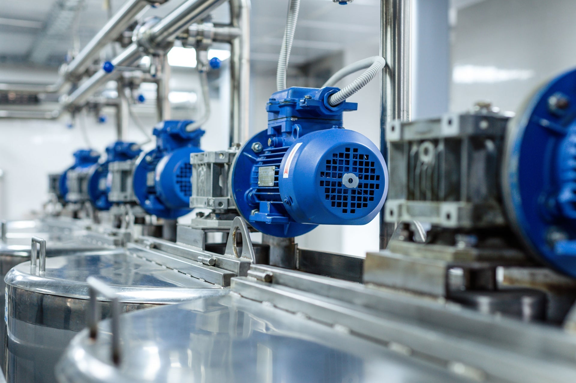 Varios motores Tausend colocados en cadena, de motor azul, en una planta de producción de algún tipo de bebida